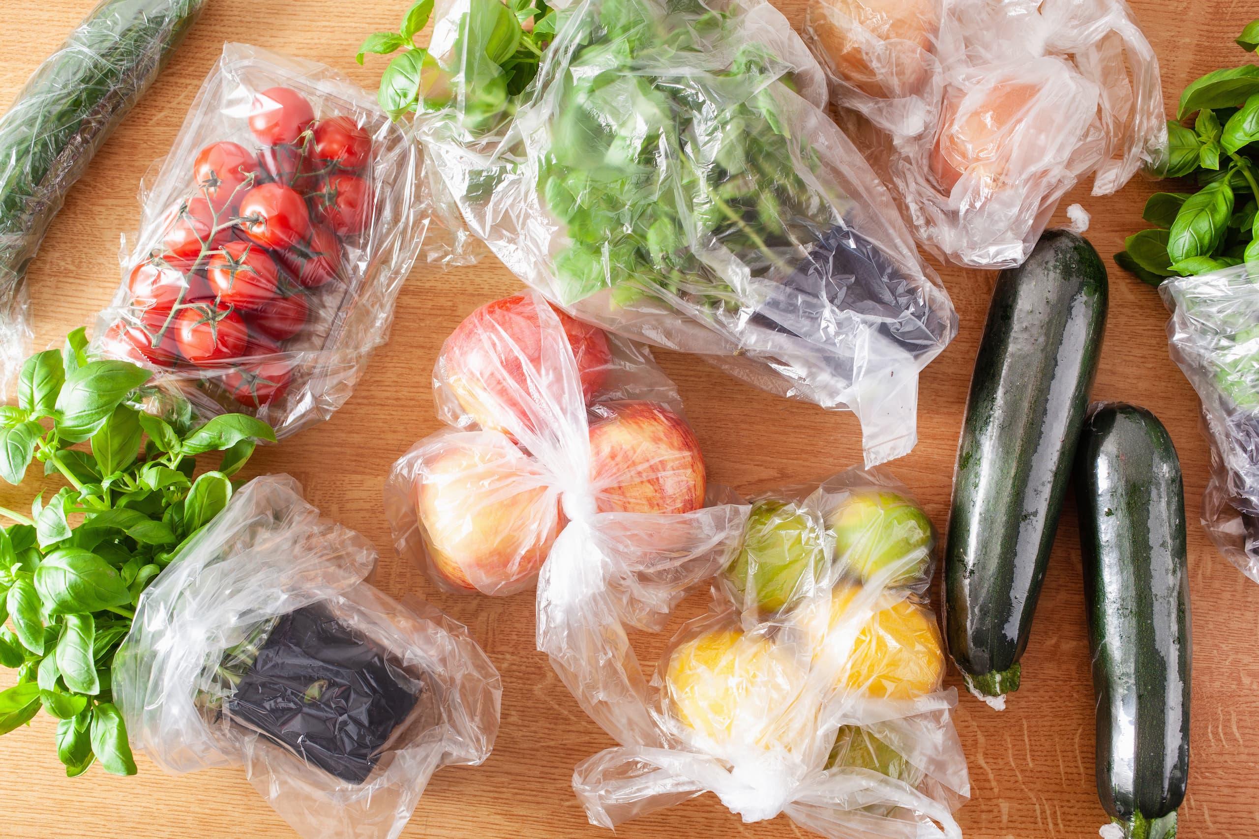 Top-down view of fruits and vegetables in plastic bags on a table
