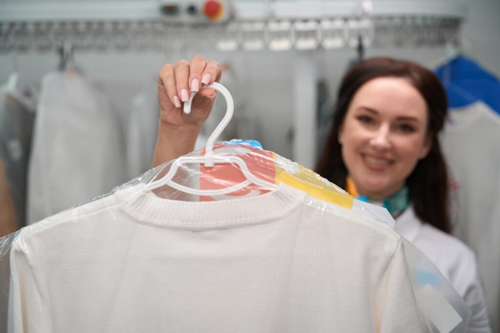 A woman holding out garment bags with shirts in them